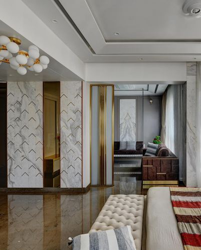 Marble foyer with chevron brass inlay leading to living room with swing seat and chandelier