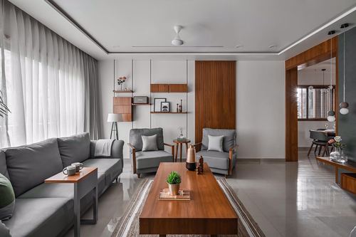 Minimalist grey living room with wooden coffee table, shelving, and sheer curtains lit by daylight
