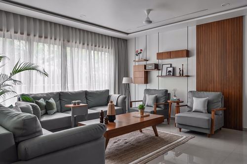 L-shaped grey sofa facing wood-panelled wall with shelving in bright living room