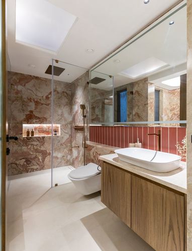Pink-veined stone bathroom with wood vanity, vessel sink, and glass shower enclosure