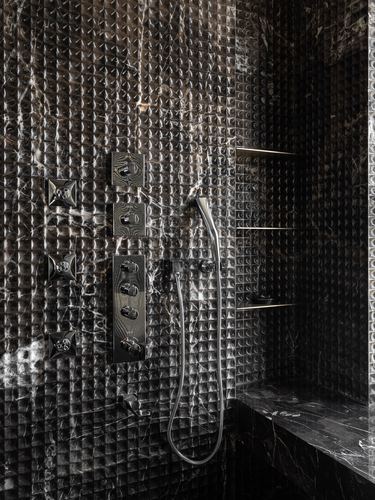 Dark textured stone shower wall with body jets, handheld shower and recessed niche shelves