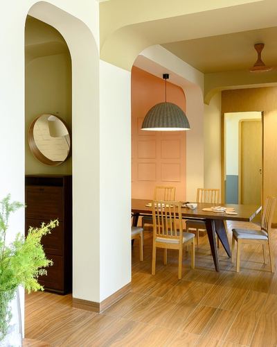 Arched doorway leads to a peach-walled dining room with wooden table and dome pendant light