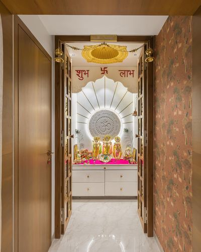 Framed pooja room with backlit sunburst niche, om medallion, deities, and gold arch entrance