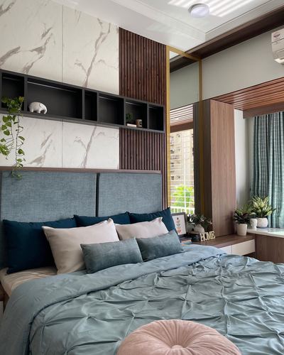 Bedroom with blue upholstered headboard, marble wall panel, wood slats, and teal bedding