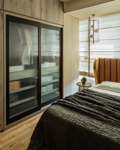 Bedroom with fluted glass wardrobe, mustard channel headboard, brass pendant light and olive bedding