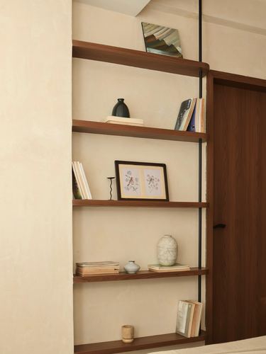 Wooden floating shelves against textured beige wall styled with vases, books, and framed art