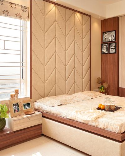 Bedroom with chevron-patterned beige upholstered headboard wall and walnut bed frame, morning light from window