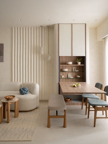 Neutral dining and living area with fluted wall, wood dining table, blue chairs, and boucle sofa