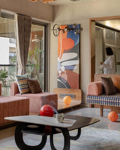 Living room with pink velvet sofas, black sculptural coffee table, and tall abstract painting on concrete wall