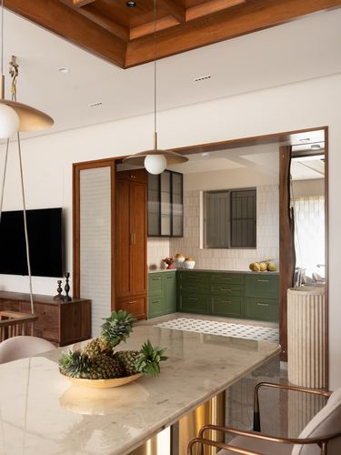 Open-plan dining counter looking through wood archway into green kitchen with patterned floor