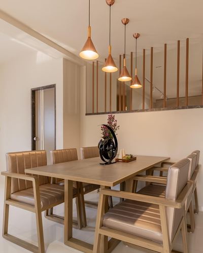Wooden dining table with leather chairs under staggered copper pendant lights