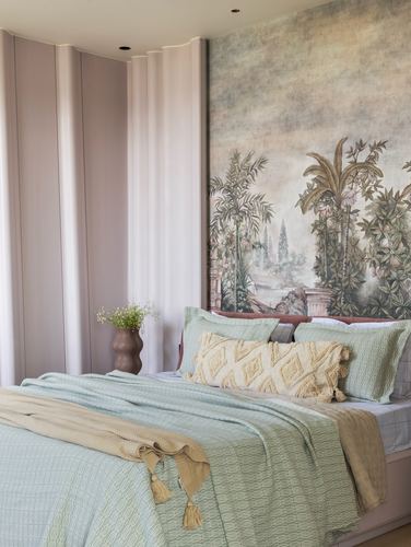 Bedroom corner with sage green bedding and a large botanical mural above the headboard