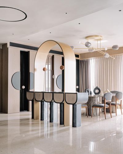 Arched gold console with marble legs stands between foyer and dining area in Kolkata home