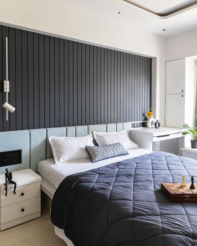 Bedroom with fluted charcoal panel wall, pastel blue upholstered headboard, and navy quilted bedding
