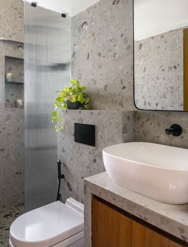 Terrazzo bathroom with fluted glass shower screen, oval vessel sink, wood vanity and black fixtures