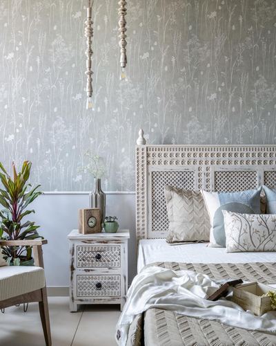Bedroom with carved wooden headboard, distressed nightstand, and botanical wallpaper wall