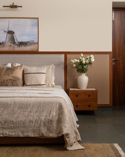 Earthy bedroom with textured headboard, linen bedding, wooden nightstand and white rose vase
