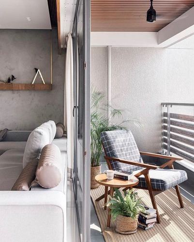 Living room with grey sofa opening through glass doors to a balcony with a plaid armchair