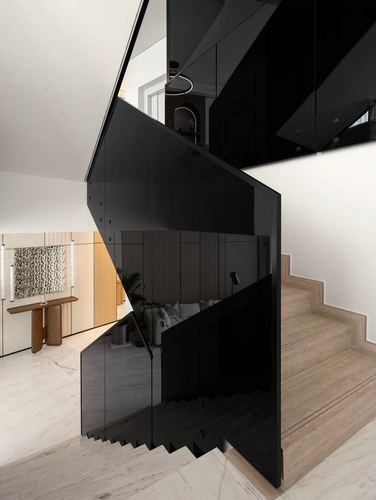 Black glass staircase balustrade over marble floor with living room glimpsed beyond