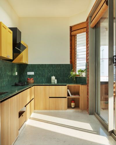 L-shaped kitchen with green tiled backsplash, mustard cabinets, and sunlit sliding glass door
