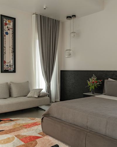 Neutral bedroom with grey sofa, textured headboard wall, and colorful stained-glass artwork