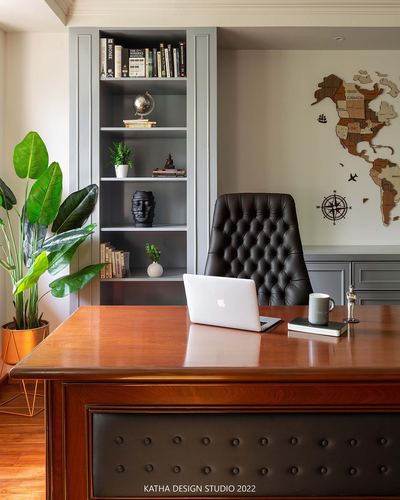 Study with wooden desk, tufted leather chair, and built-in bookshelf with decor