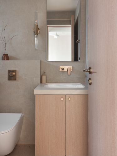 Minimalist bathroom with wood vanity, brass fixtures, recessed mirror niche, and freestanding tub