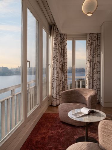 Curved armchair and marble side table beside floor-to-ceiling windows overlooking the Nile in Cairo