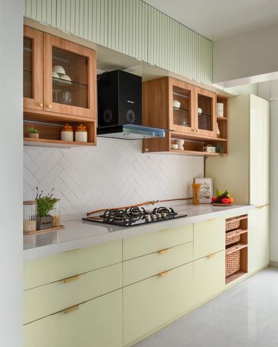 Pastel yellow kitchen with wood upper cabinets, herringbone tile backsplash, and black chimney hood