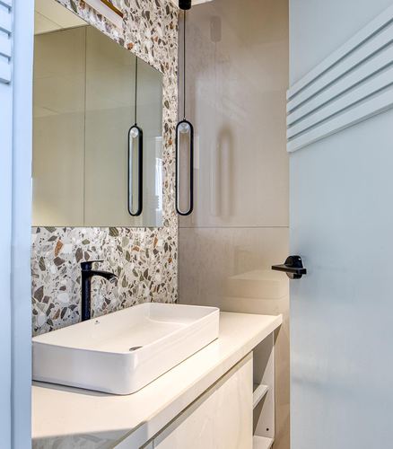 Bathroom vanity with terrazzo backsplash, rectangular vessel sink, and two black pendant lights.