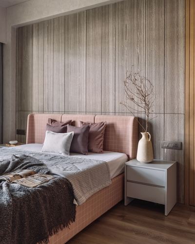 Bedroom with pink upholstered bed against ribbed wood panel wall and grey nightstand