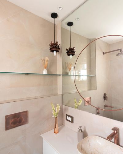 Beige stone bathroom with copper fixtures, round mirror and lotus-shaped pendant light over vessel sink
