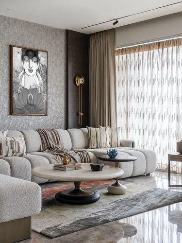 Curved cream boucle sectional sofa beside round marble coffee table in softly lit living room