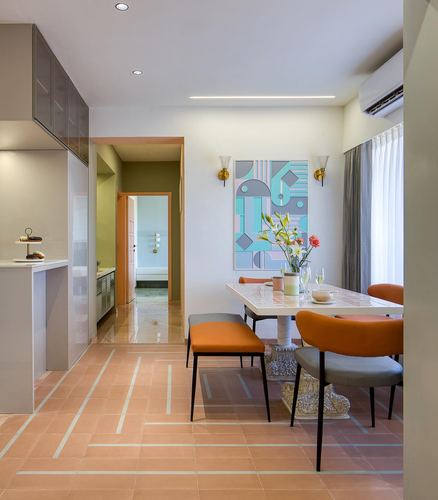 Dining area with terracotta patterned floor, orange chairs, and colorful geometric art above table