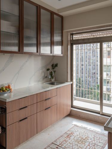 Kitchen with wood cabinetry, marbled backsplash, and city view through sliding glass door