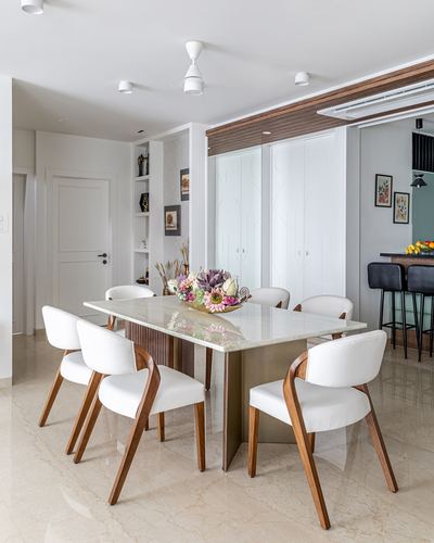 Dining room with marble-top table, curved wood chairs, and a view into a kitchen bar area