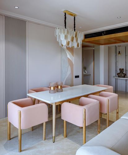 Dining room with marble-look table, pink velvet chairs, and cluster chandelier over abstract mural.
