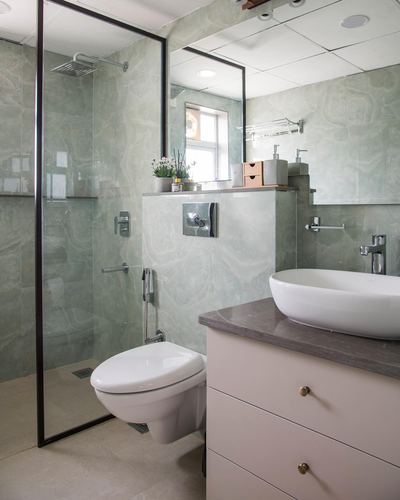 Sage marble-look bathroom with glass shower, wall-hung toilet, and vessel sink vanity
