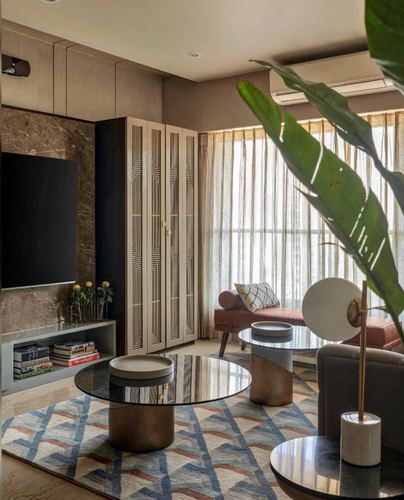Living room with fluted deco cabinet, stone tv wall, round brass tables and geometric rug