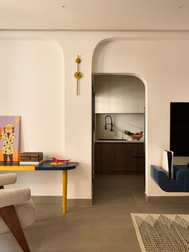 Living room with arched doorway leading to kitchen, mustard console table, wall clock