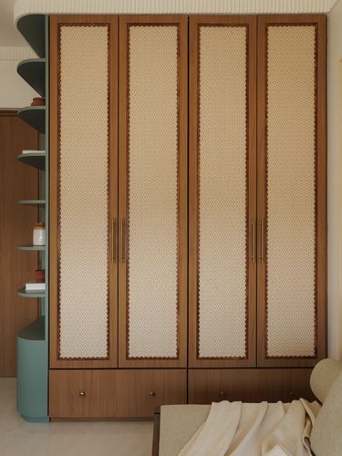 Wood wardrobe with cane-panel doors and brass handles beside a curved teal shelving unit