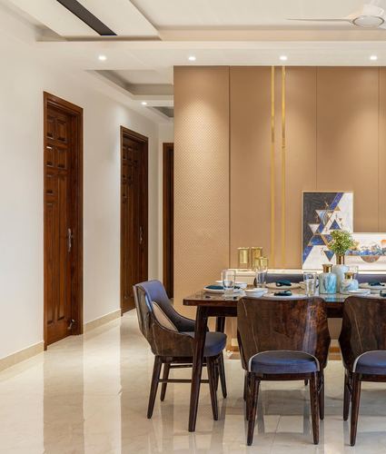 Dining area with dark wood table, navy chairs, and a textured buff feature wall with brass inlays