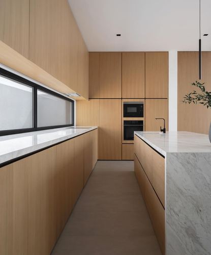 Galley kitchen with wood veneer cabinetry, marble island, and horizontal window strip