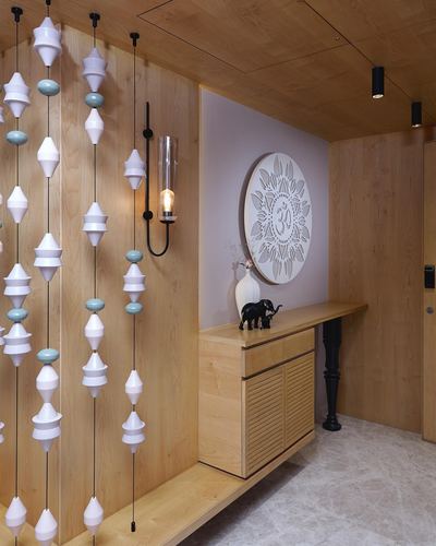 Wood-paneled foyer with hanging ceramic pendant strands, mandala wall art, and console table