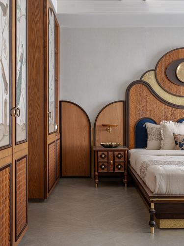 Bedroom with arched carved headboard, patterned wood wardrobes, and stone floor