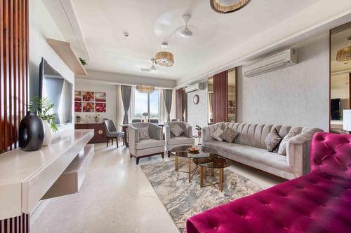 Living room with grey tufted sofa, magenta velvet bench, glass coffee table and fluted wood console