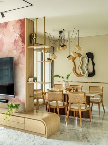 Open dining and living area with cane chairs, sculptural pendant lights, and pink marble accent wall