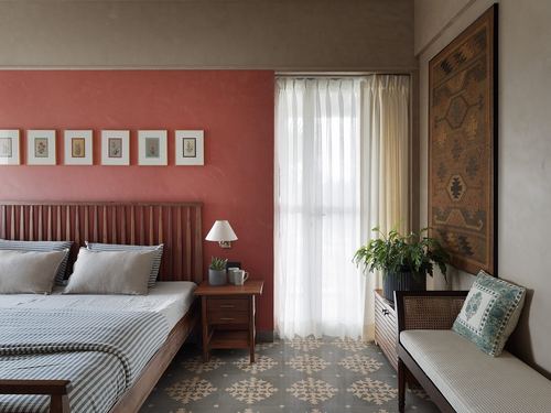 Bedroom with terracotta wall, slatted wood headboard, patterned floor tiles, and cane bench