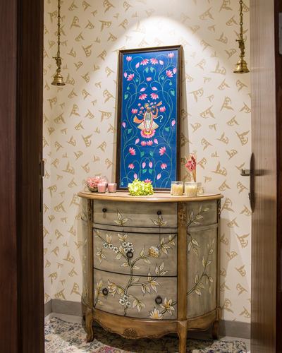 Hand-painted demilune console below a spotlit blue floral devotional painting in a patterned foyer
