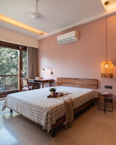 Bedroom with pink patterned wall, wooden bed, cane pendant lights, and balcony view